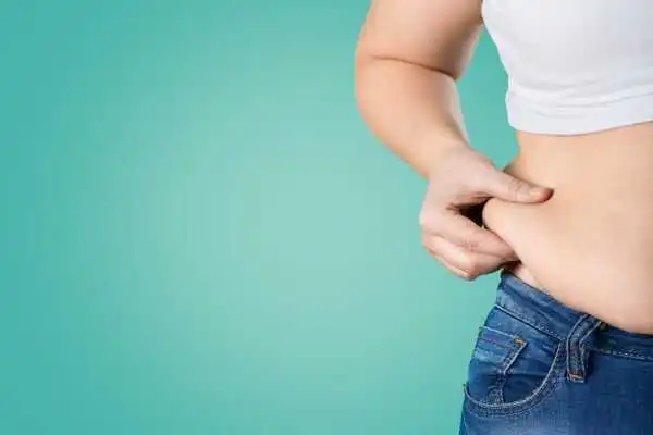 Image of woman pinching her love handles to show weight gain Boston